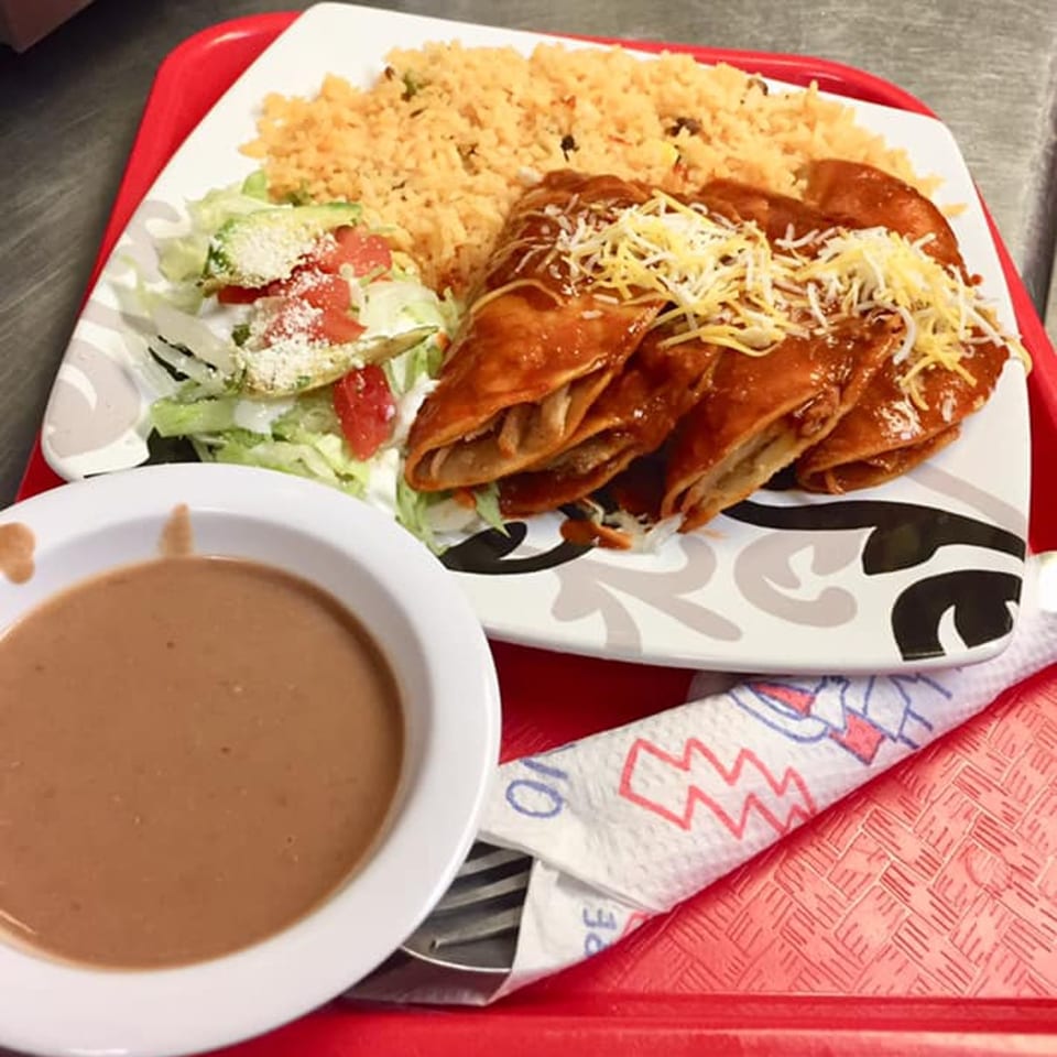 A Tacontento Mexican combo plate with enchiladas, rice, salad, and a side of refried beans.