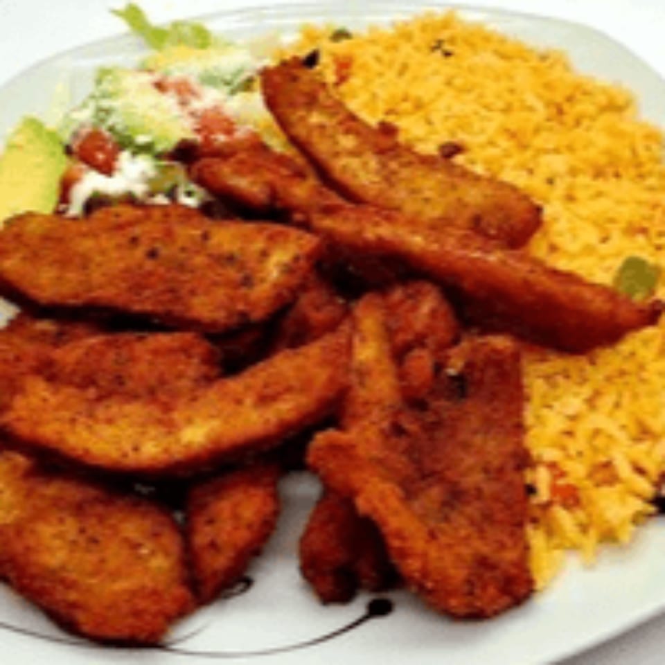 Crispy chicken strips, yellow rice, and a fresh salad with avocado on a white plate.